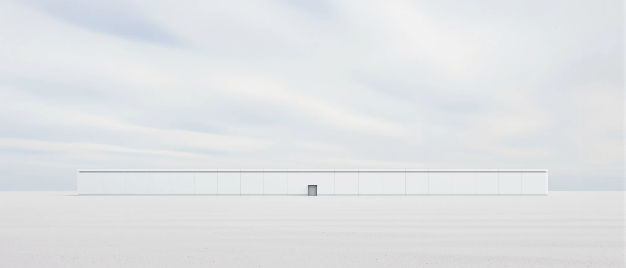 A long, low white data center building alone on a pale plain under clouds streaking across the sky
